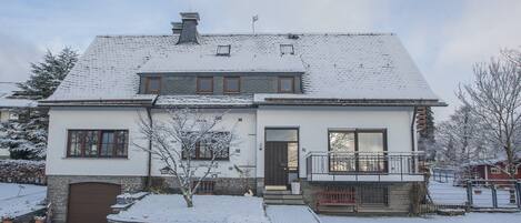 A two-story house with a snow-covered roof and a brick facade.