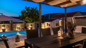 Un espace extérieur aménagé avec une terrasse, une piscine, une table à manger, des chaises et des parasols.