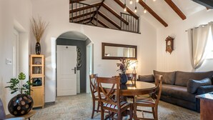 Un coin repas avec une table ronde et des chaises, un escalier, un canapé et une bibliothèque.