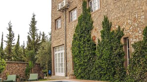 A stone building with a swimming pool, outdoor seating, and greenery. - Sakia Talamanzou (Gmassa)