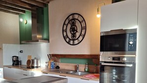 Eine moderne Küche mit einer Stein Arbeitsplatte, einer Uhr und integrierten Geräten.