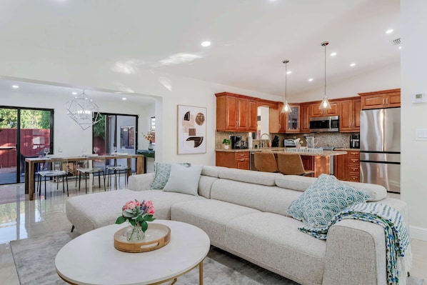 A modern kitchen with stainless steel appliances, wooden cabinets, and pendant lighting.
