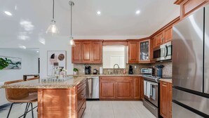 Cozinha moderna com armários de madeira, eletrodomésticos de aço inoxidável e uma ilha central.