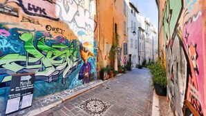 Une ruelle étroite, dont les murs sont ornés de graffitis colorés, et sur laquelle on peut voir une enseigne indiquant un restaurant.