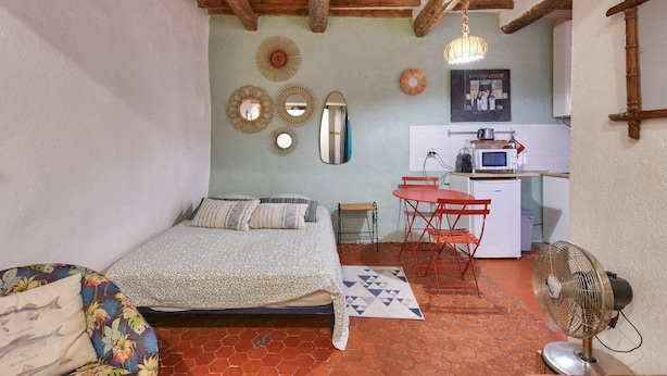 Une chambre confortable avec un lit, une petite table et un coin cuisine.