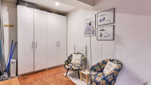 Une pièce comprenant une grande armoire, deux fauteuils à motifs floraux, un radiateur et deux tableaux encadrés accrochés au mur.