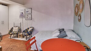 Une pièce confortable avec un lit, deux chaises, une petite table et un ventilateur.