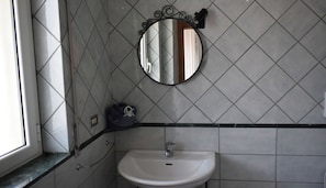 Une salle de bain avec un lavabo blanc, un miroir et une fenêtre.