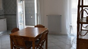 Ett kök med ett matbord och stolar, en spis, en ugn och ett fönster med gardiner.