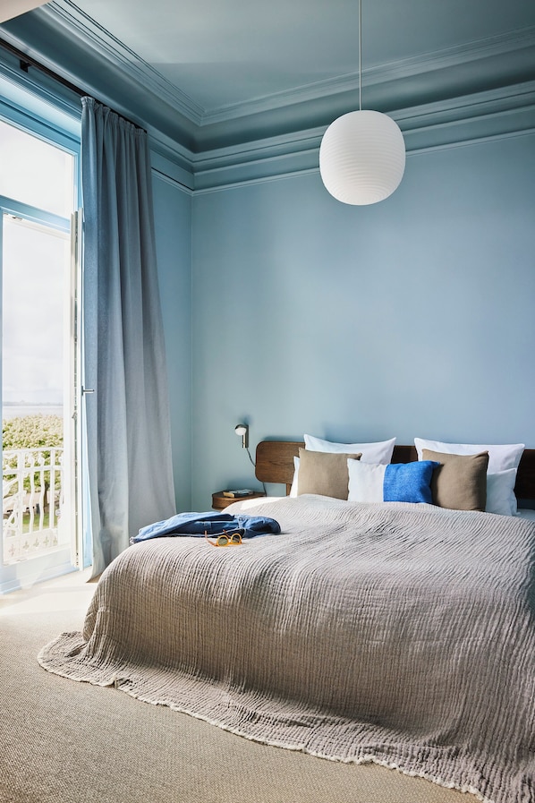Un dormitorio con una cama grande, una lámpara colgante y vistas a un balcón.