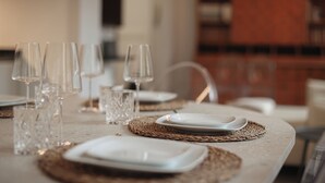 Une table à manger dressée avec de la vaisselle en verre transparent et des assiettes blanches, agrémentée de sets de table en fibres tressées.