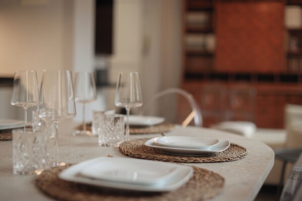 A dining table set with clear glassware and white plates, with woven placemats. - (New) Ponte Vecchio Tour (Firenze)