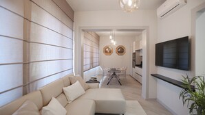 Un salon moderne comprenant un canapé d’angle, un coin repas et un téléviseur fixé au mur.