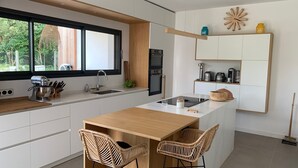 A modern kitchen with a central island, white cabinetry, and a window overlooking greenery.