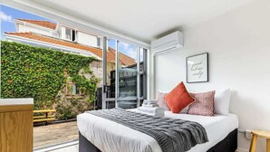 Un dormitorio con una cama grande, vistas a un jardín y un ventanal corredero.