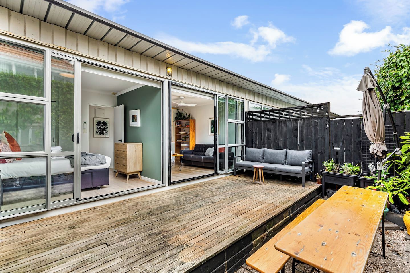 A modern house with a wooden deck, a sofa, and a dining table.