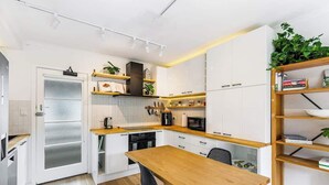 Una cocina moderna con armarios blancos, una mesa de comedor de madera y una estantería empotrada.