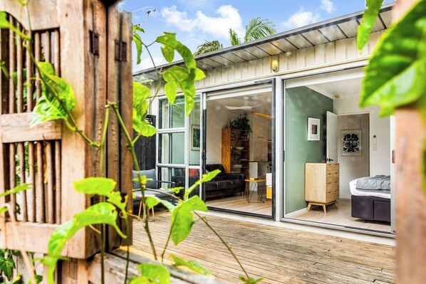 A modern house with a glass door leading to a living area with a sofa, a coffee table, and a bookshelf.