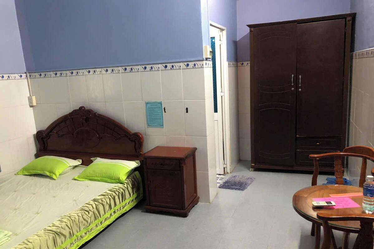 Ein Schlafzimmer mit einem Bett, einem Nachttisch aus Holz, einem Kleiderschrank und einem kleinen Tisch mit Stuhl.