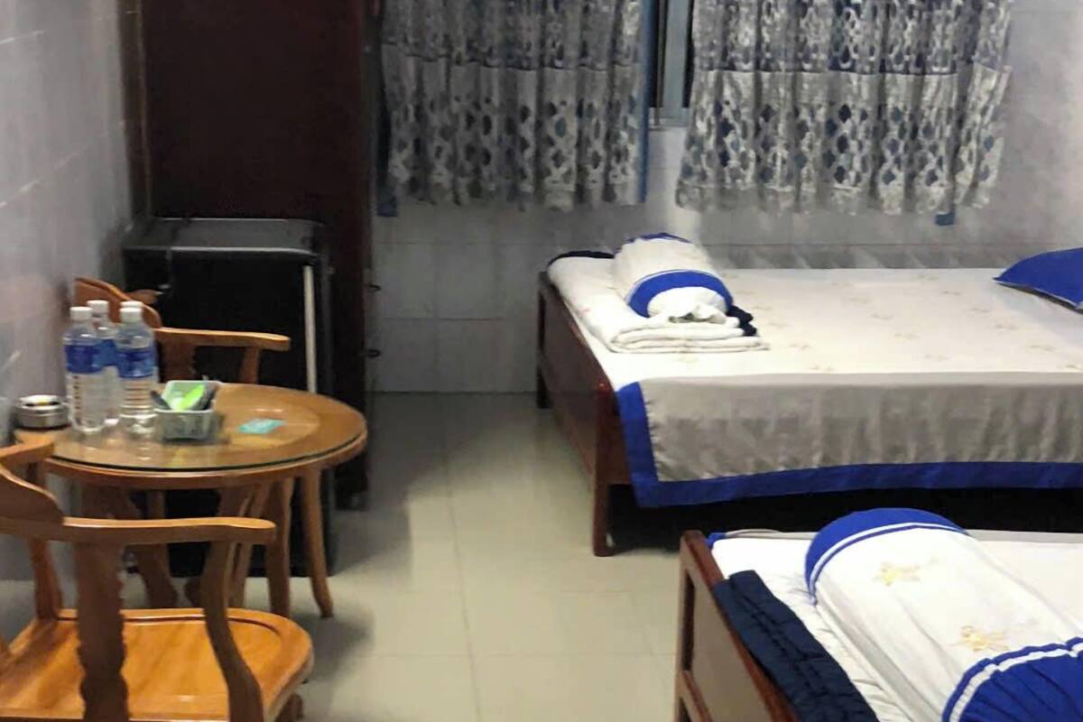 Ein Hotelzimmer mit Bett, einem kleinen Tisch mit Stühlen, einem Schreibtisch und einem Fenster mit Vorhängen.