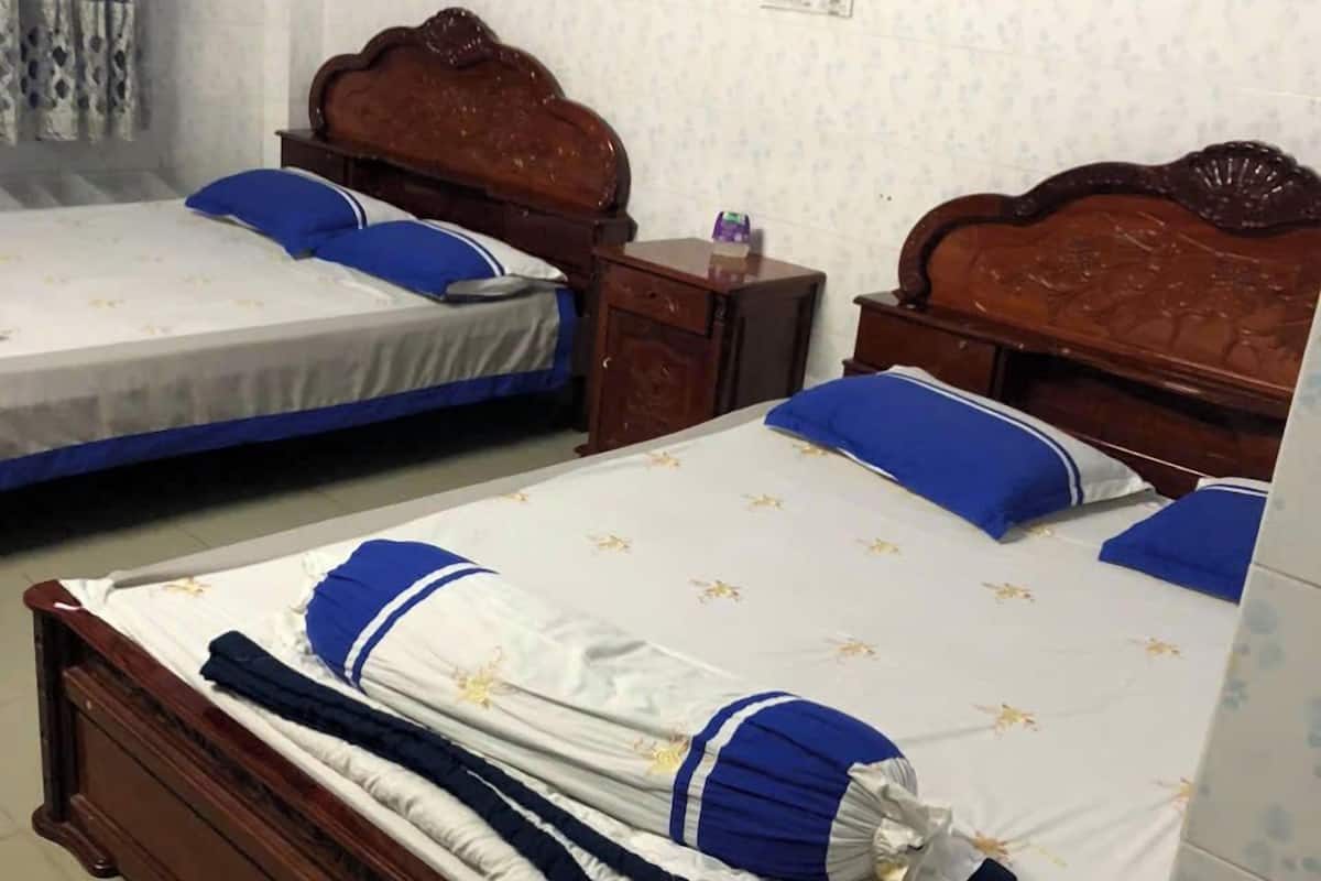 Ein Hotelzimmer mit zwei hölzernen Betten, jeweils mit einer blau-weißen Tagesdecke und passenden Kissen.