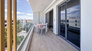 A balcony with a table and chairs, a sliding glass door, and a view of the cityscape. - Gorgeous Penthouse with Rooftop and Ocean Views (Punta Cana)
