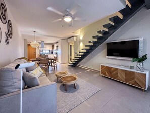 Ein modernes Wohnzimmer mit einer Couch, einem Couchtisch, einem Fernseher und einer Treppe.