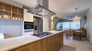 A modern kitchen with a central island, built-in oven, and stainless steel appliances. - Gorgeous Penthouse with Rooftop and Ocean Views (Punta Cana)