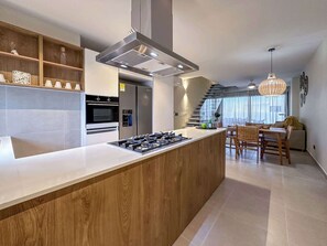 Eine moderne Küche mit Kochinsel, eingebautem Backofen und Edelstahlgeräten.