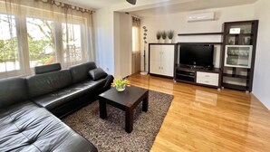 A modern living room with a leather sofa, a coffee table with a vase, a TV, and a cabinet with decorative items.