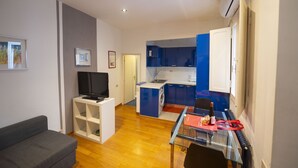 A compact living space with a kitchenette, a sofa, a TV, and a dining area. - Cozy 2BR Apartment near Piazza Navona (Roma)