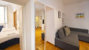 A modern living room with a grey sofa, a wooden floor, and a white wall with a framed picture. - Cozy 2BR Apartment near Piazza Navona (Roma)