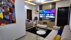 Ein modernes Wohnzimmer mit Flachbildfernseher, einer Couch, einem Couchtisch und einem dekorativen Gemälde.
