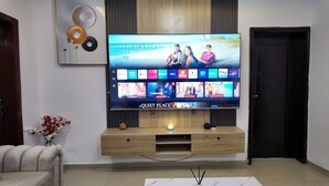 Ein Flachbildfernseher an einem hölzernen Standfuß, darüber ein dekoratives Wandbild.