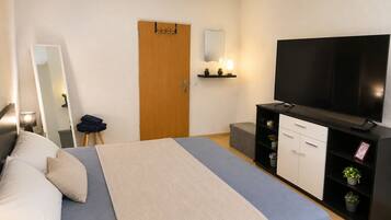 Una habitación de hotel con cama, televisión, armario y puerta.
