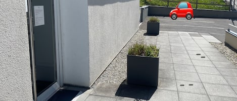 En byggnads entré med en skylt, en röd bil parkerad utanför och ett berg i bakgrunden.