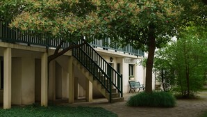 Ein Gebäude mit einer überdachten Außentreppe, einer Bank und einem gepflegten Garten.