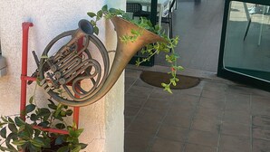 Una planta en maceta sobre un soporte de metal rojo, con una gran escultura de cuerno apoyada contra la pared.