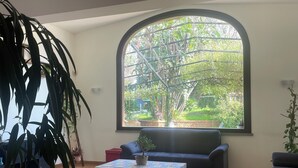 Una sala de estar con un gran ventanal arqueado, un sofá, una mesita de centro y una planta en maceta.