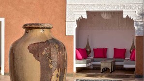 Eine große Vase, ein Pool und eine Sitzecke mit Kissen.
