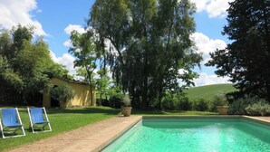 A rectangular swimming pool with clear water, surrounded by a brick deck. There are two blue lounge chairs on the left side of the pool. - Authentic Tuscan farmhouse with pool for families and children (Toscana)