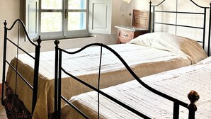 A room with two beds, a window with shutters, a bedside lamp, and a wooden ceiling. - Authentic Tuscan farmhouse with pool for families and children (Toscana)