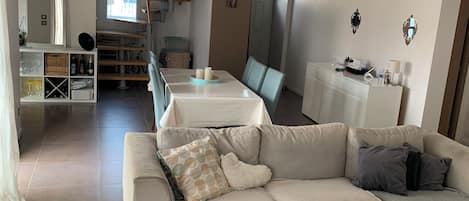 A modern living room with a sectional sofa, a coffee table, and a dining area with a table and chairs.