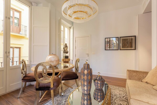 A well-lit living room with a round table, two chairs, a sofa, and decorative items. - Luxury BibRambla Apartment (granada)