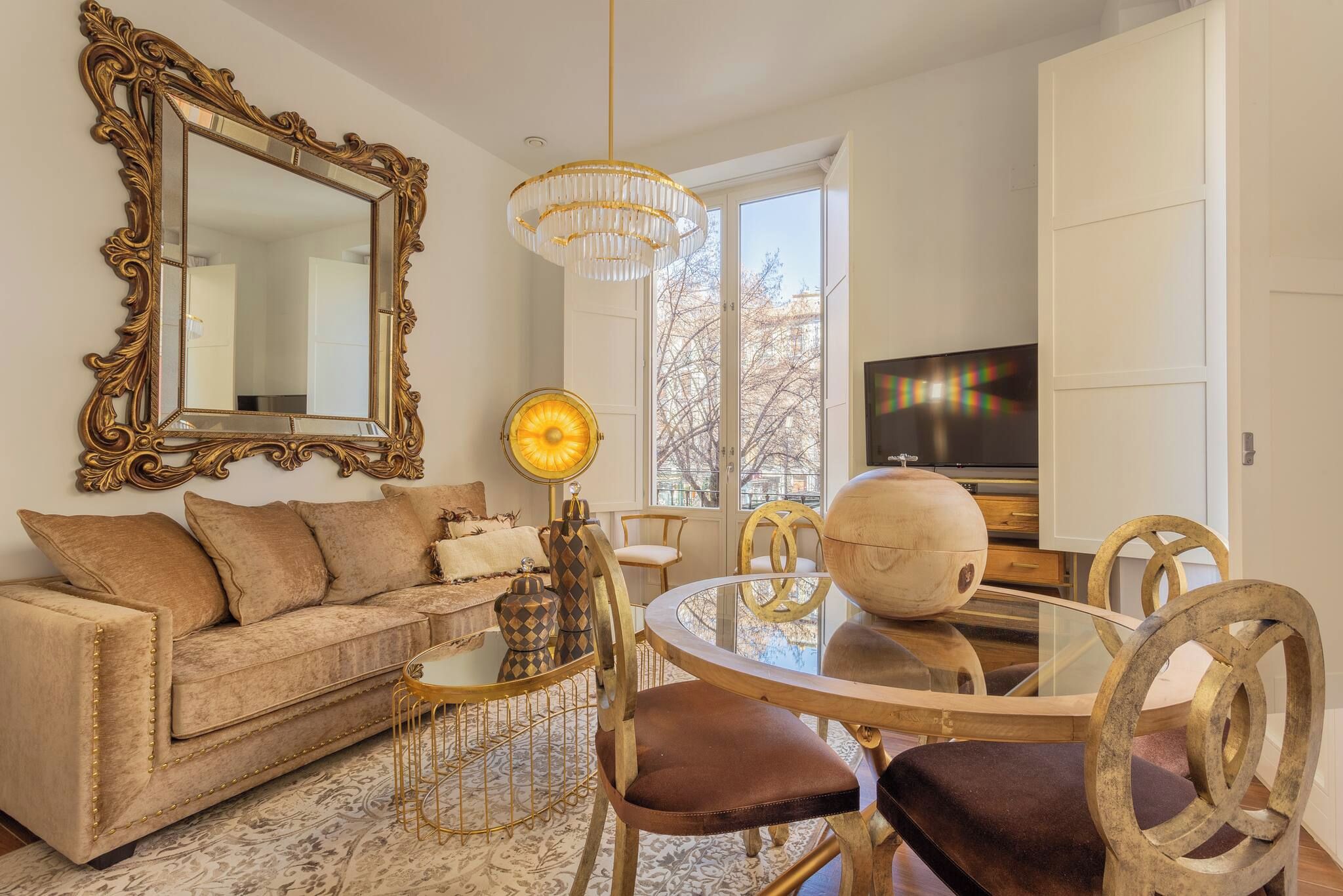 Un salon comprenant un canapé, une table à manger ronde, des chaises, un téléviseur et un grand miroir.