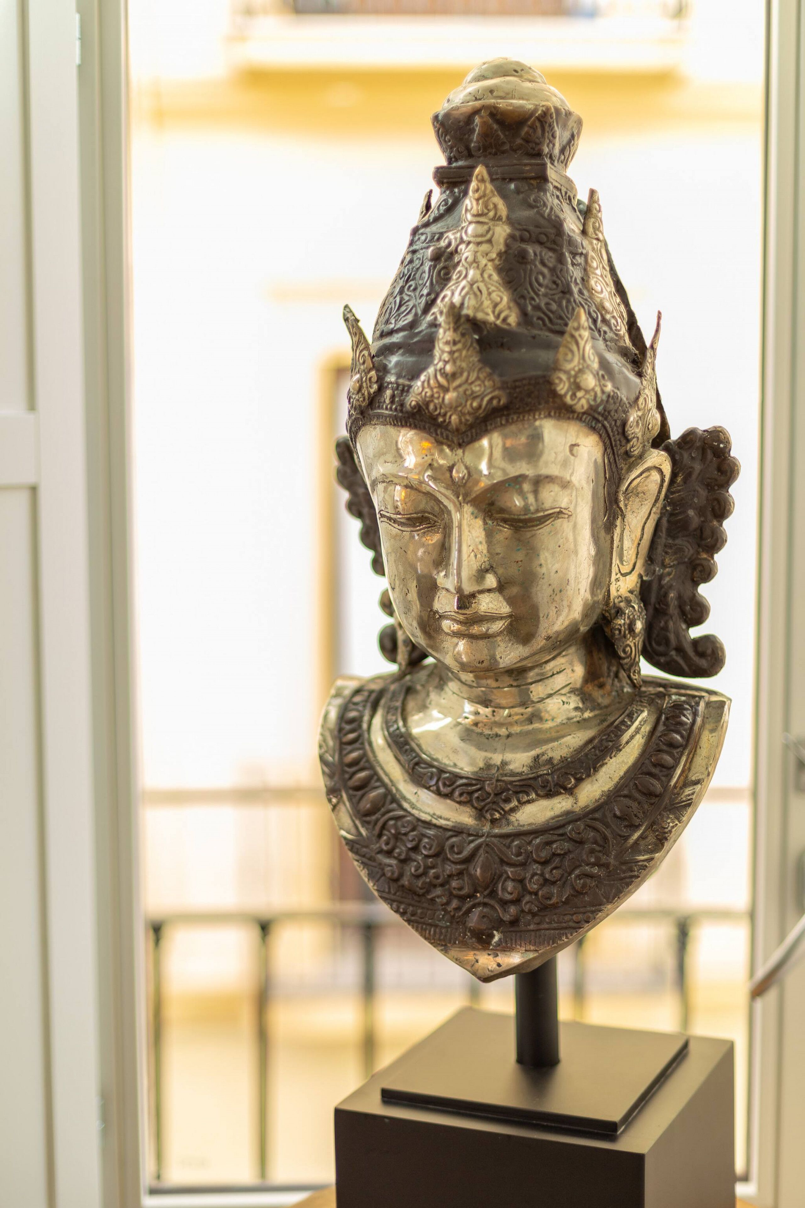 A sculpture of a figure with intricate designs on the headpiece and shoulders, placed on a pedestal.