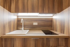 Una cocina moderna con un lavamanos empotrado, un grifo, una placa de inducción y armarios de madera.