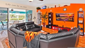 A living room with a leather sofa, a TV, and a bookshelf.