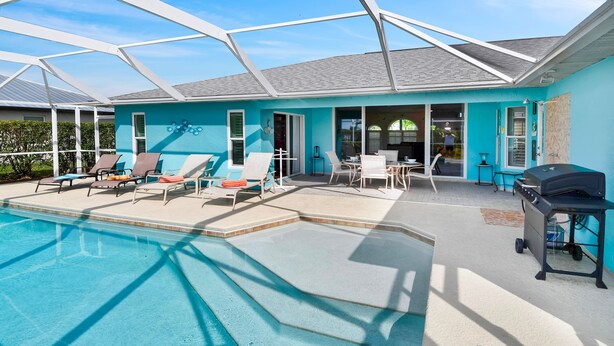 A pool area with lounge chairs and a grill, enclosed by a glass structure.
