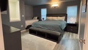 A bedroom with a large bed, a smaller bed, a bench, a nightstand, and a dresser. - Luxury modern apartment (Willits)